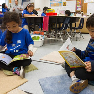 an image of young kids reading books on the classroom floor together
